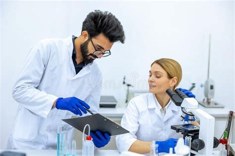 Woman And Man Scientists In Lab Coat Making Notes After Doing Sample