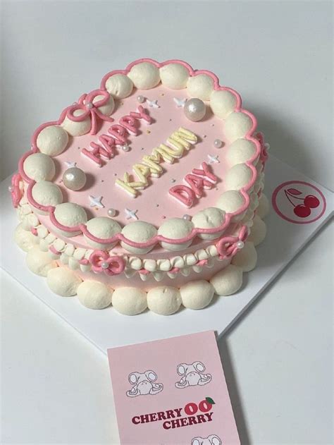 A Pink And White Birthday Cake Sitting On Top Of A Table Next To A Card