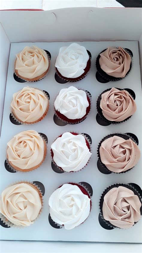 Twelve Cupcakes In A Box With Frosting On Top And Rose Decorations