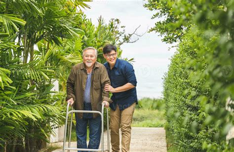 Caregiver Is Teaching Old Man To Walk With Walker Senior Asian Father