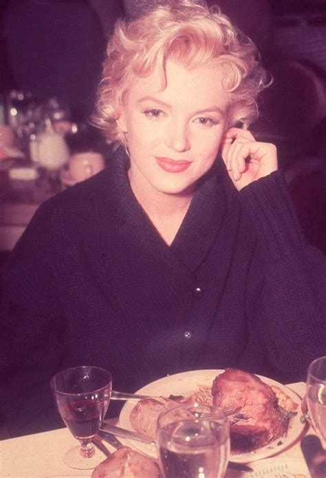 A Woman Sitting At A Table With Food In Front Of Her And Wine Glasses