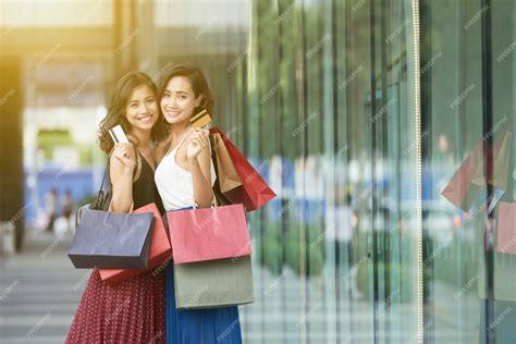 Free Photo | Side view of two ladies shopping standing in a mall with credit cards