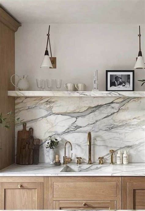 A Kitchen With Marble Counter Tops And Wooden Cabinets