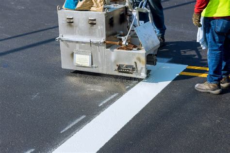 Workers Apply A Road Marking To The Stripe With White Paint And