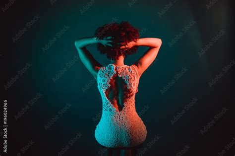 Beautiful Black Woman With Curly Hair Showing Her Naked Back Wearing A White Dress In A Studio
