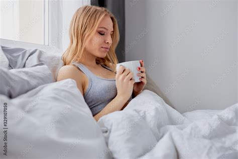 Cute Girl Lie On Bed And Drink A Cup Of Hot Coffee Or Tea Lady With Blond Short Hair In