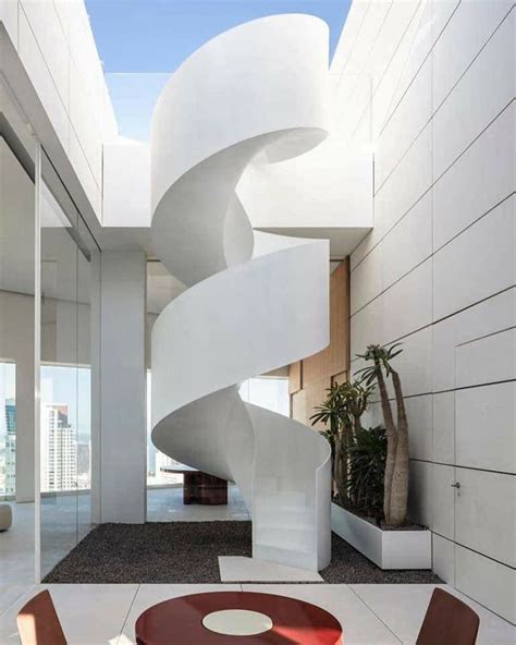 A Spiral Staircase In The Middle Of A Room With Two Chairs And A Round