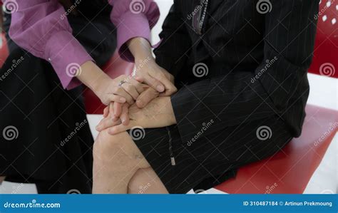 Two Women Are Sitting On A Red Chair One Of Them Is Touching Other S