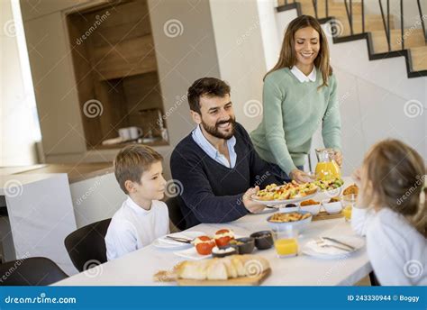 Familia Joven Y Feliz Hablando Mientras Desayuna En La Mesa Foto De