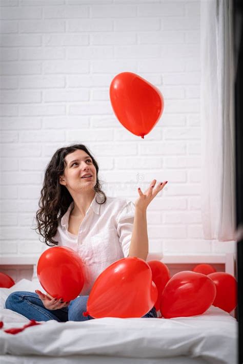 Brunette European Girl Rejoices Playing On Bed With Red Heart Shape Balloons Morning Love