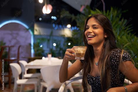 Mujer Joven latina de cabello castaño largo tomando cafe sentada Stock