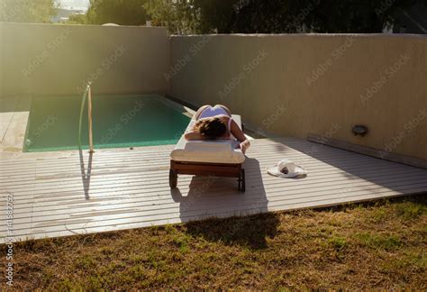 Foto Stock Beautiful Naked Girl Is Lying On A Lounger By The Pool And Sunbathing At Sunset