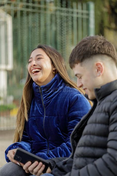 Latina Girl Laughing Sitting On A Plaza Bench With Her Boyfriend Stock Photo Image Of