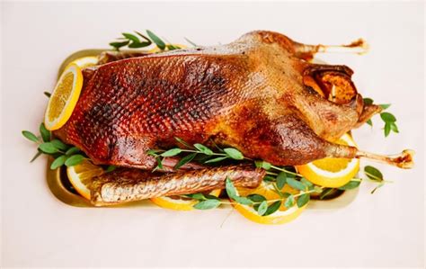 Premium Photo Roasted Goose With Oranges On A Golden Tray For