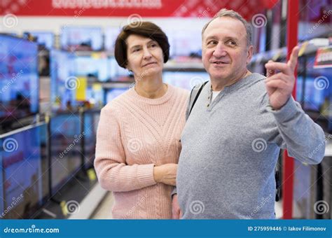 Middle Aged Man And Woman Choosing Tv In Electronic Store Stock Photo