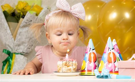 Premium Photo A Twoyearold Girl Blows Out A Candle On A Birthday Cake