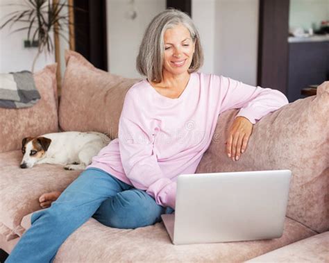 Mature Woman Using Wireless Laptop Apps Browsing Internet Sit On Sofa