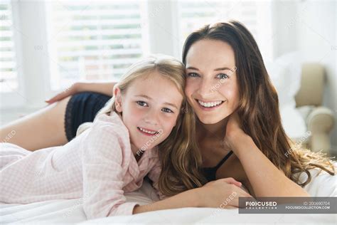 Portrait Smiling Mother And Daughter Laying On Bed — Morning Pajamas