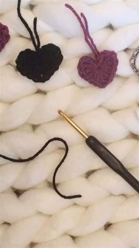 Crocheted Hearts And Other Items Are Laying On A White Knitted Surface