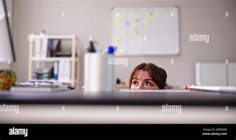 Scared Woman Hiding Behind Chair And Under Desk Stock Photo Alamy