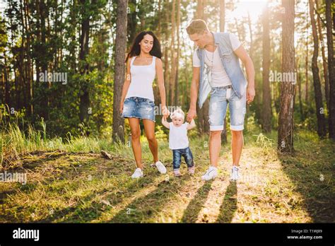 Los padres jóvenes se les enseña a caminar a su hija de un año en la