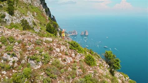 Woman Beholds Capri S Faraglioni From Rocky Summit Clad In Summer