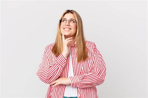 Premium Photo Curvy Pretty Blonde Woman Smiling Happily And Daydreaming Or Doubting