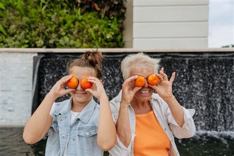 Premium Photo Happy Grandmother And Granddaughter Playing With Mandarins