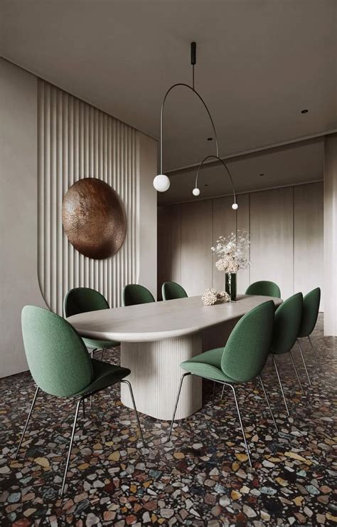 A Dining Room Table With Green Chairs And A Large Circular Light