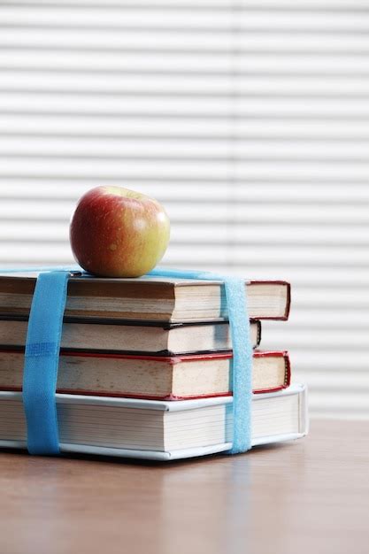 Una Manzana Y Una Pila De Libros Cerca De La Ventana Foto Premium