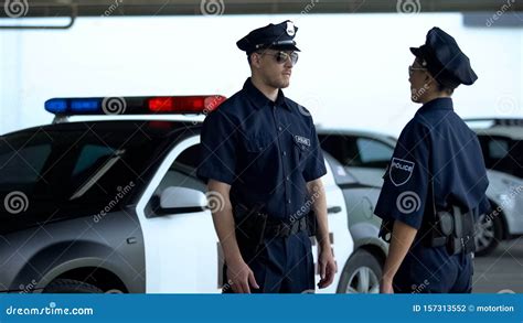 Two Serious Police Officers Communicating On Parking Lot Patrolling