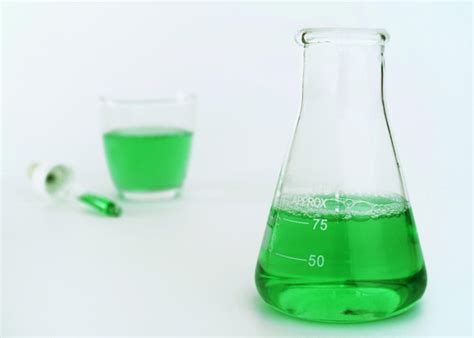 Un vaso de precipitados con líquido verde y un vaso con el número 75