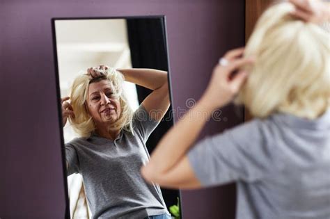 Mature Bald Woman Putting On Wig Looking In Mirror Stock Photo Image Of Confidence Bald
