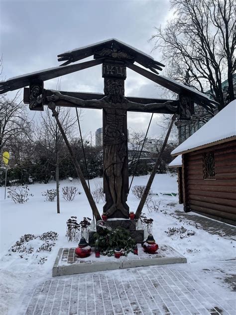 A Cross In The Middle Of A Snow Covered Yard With Christmas Decorations