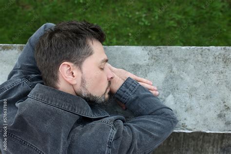 Tired man sleeping on stone parapet outdoors, top view. Space for text Stock Photo | Adobe Stock