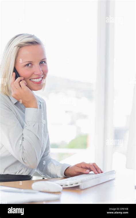 Blonde Businesswoman On The Phone Smiling At Camera Stock Photo Alamy