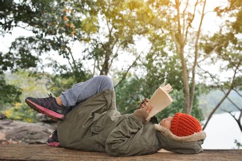 Premium Photo | Side view of boy reading book while lying on wood