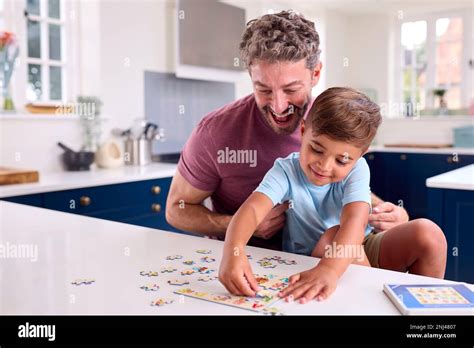 Mature Father At Home In Kitchen With Son Doing Jigsaw Puzzle Together Stock Photo Alamy