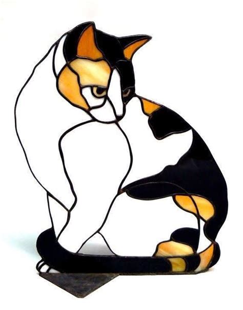 A Stained Glass Cat Sitting On Top Of A Black Base With Yellow And