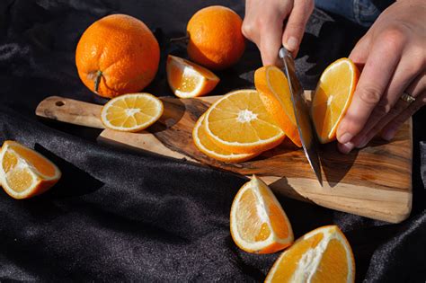 Photo Of The Orange Slicing Process A Woman Cuts An Orange With A Knife