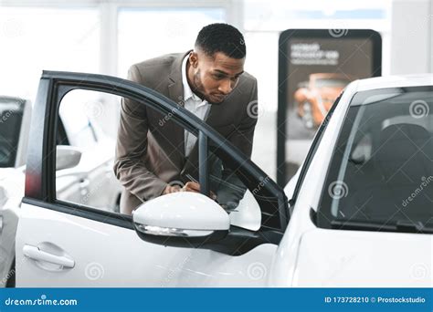 Insurance Agent Checking New Car In Dealership Showroom Stock Photo