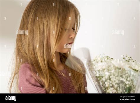 Belle Petite Fille Blonde Aux Cheveux Longs Tenant Un Fond Blanc Avec Un Bouquet De Fleurs La