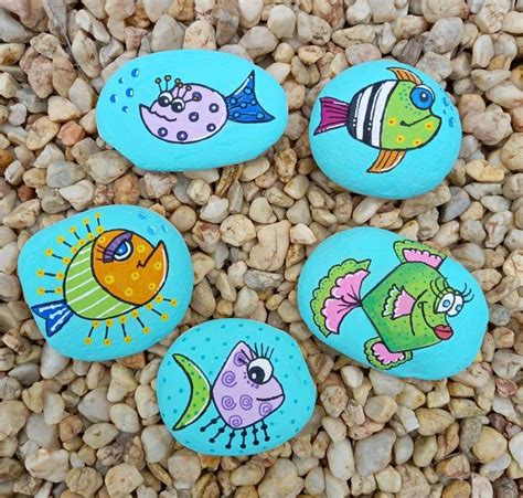 Four Painted Rocks Sitting On Top Of A Bed Of Gravel Next To Stones