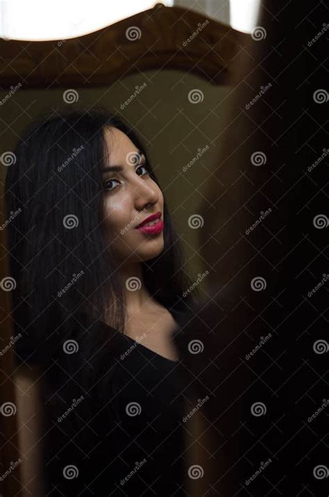 Young Charming Brunette Girl Looks At Her Reflection In The Mirror