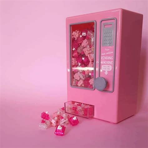 A Pink Vending Machine Sitting On Top Of A Table Next To Gummy Bears