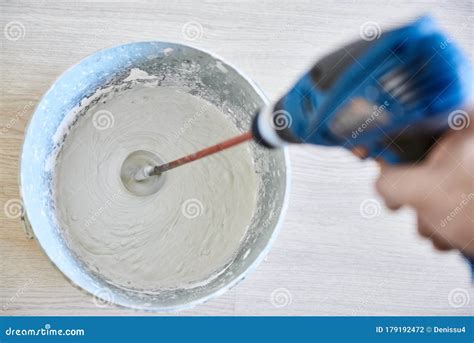 Worker Mixing Plaster In Bucket Using An Electric Drill Stock Photo