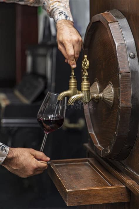 Person Pouring Wine From A Wine Barrel Mature Sommelier In Winery