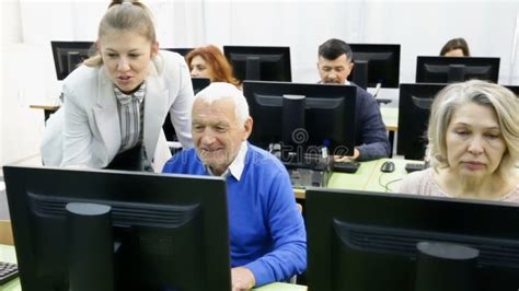 Portrait Of Modern Elderly People Working On Computers With Young