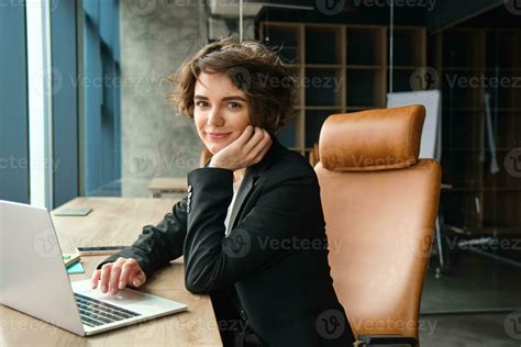 Young successful woman in business suit, sitting in her office ...