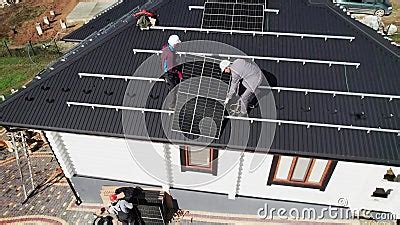 Workers Lifting Up Photovoltaic Solar Module While Installing Solar